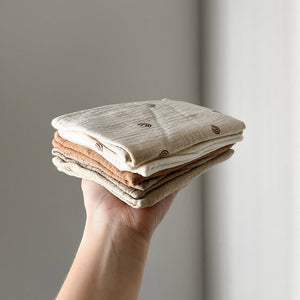 Hand holding a stack of folded fabric swatches against a neutral background