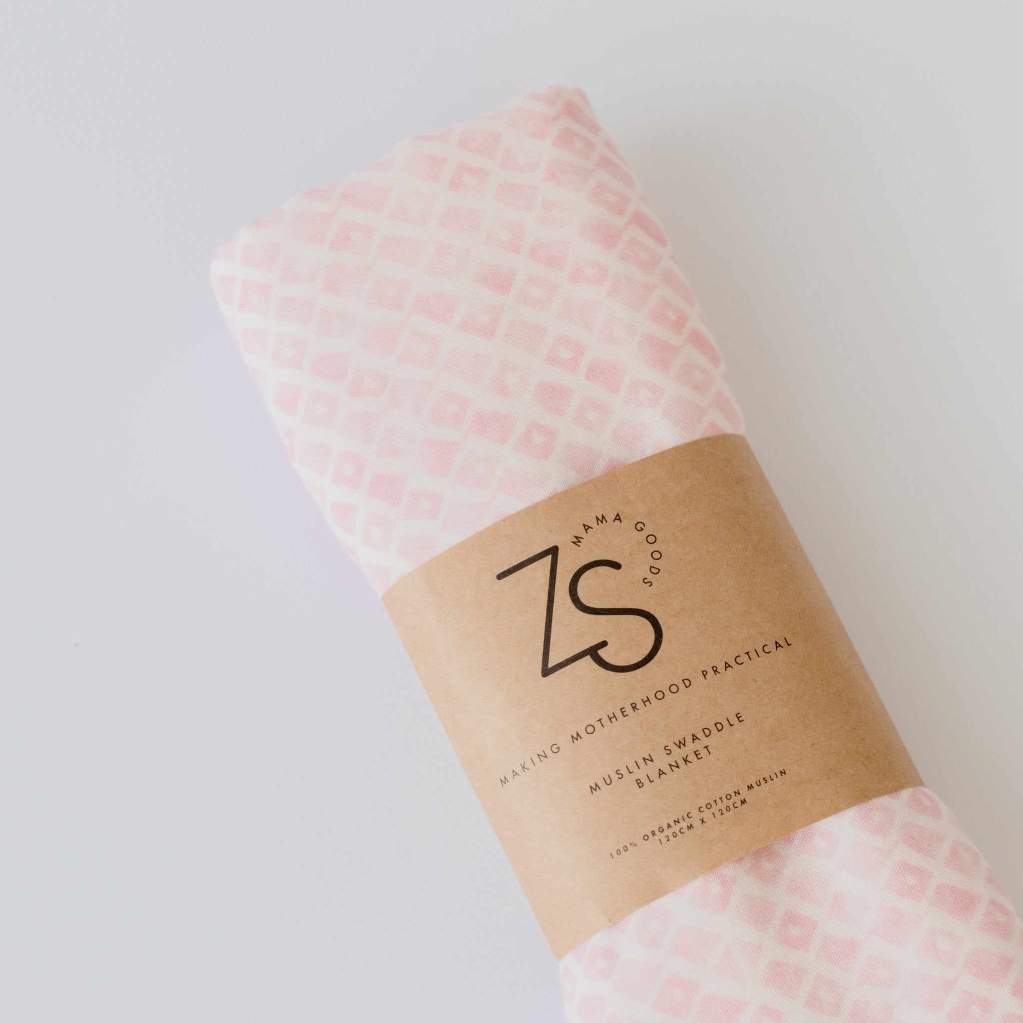 Soft organic cotton muslin swaddle wrap in rose geometric pattern draped gently.
