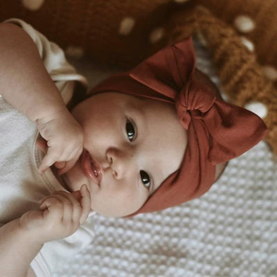 Close up of rust coloured bow knot headband for babies by Zoe Sage