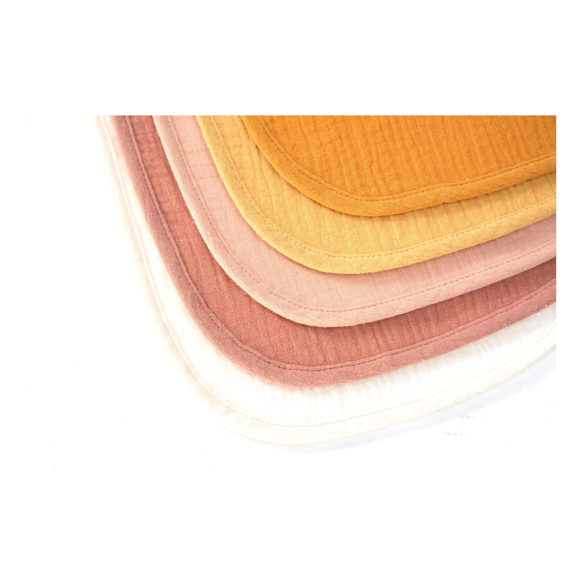 Stacked organic muslin baby bibs in Golden Harvest colours, close up of the weave