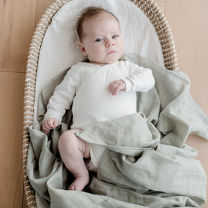 Baby wearing  on Muslin Swaddle Blanket | Sage Green (Organic)
